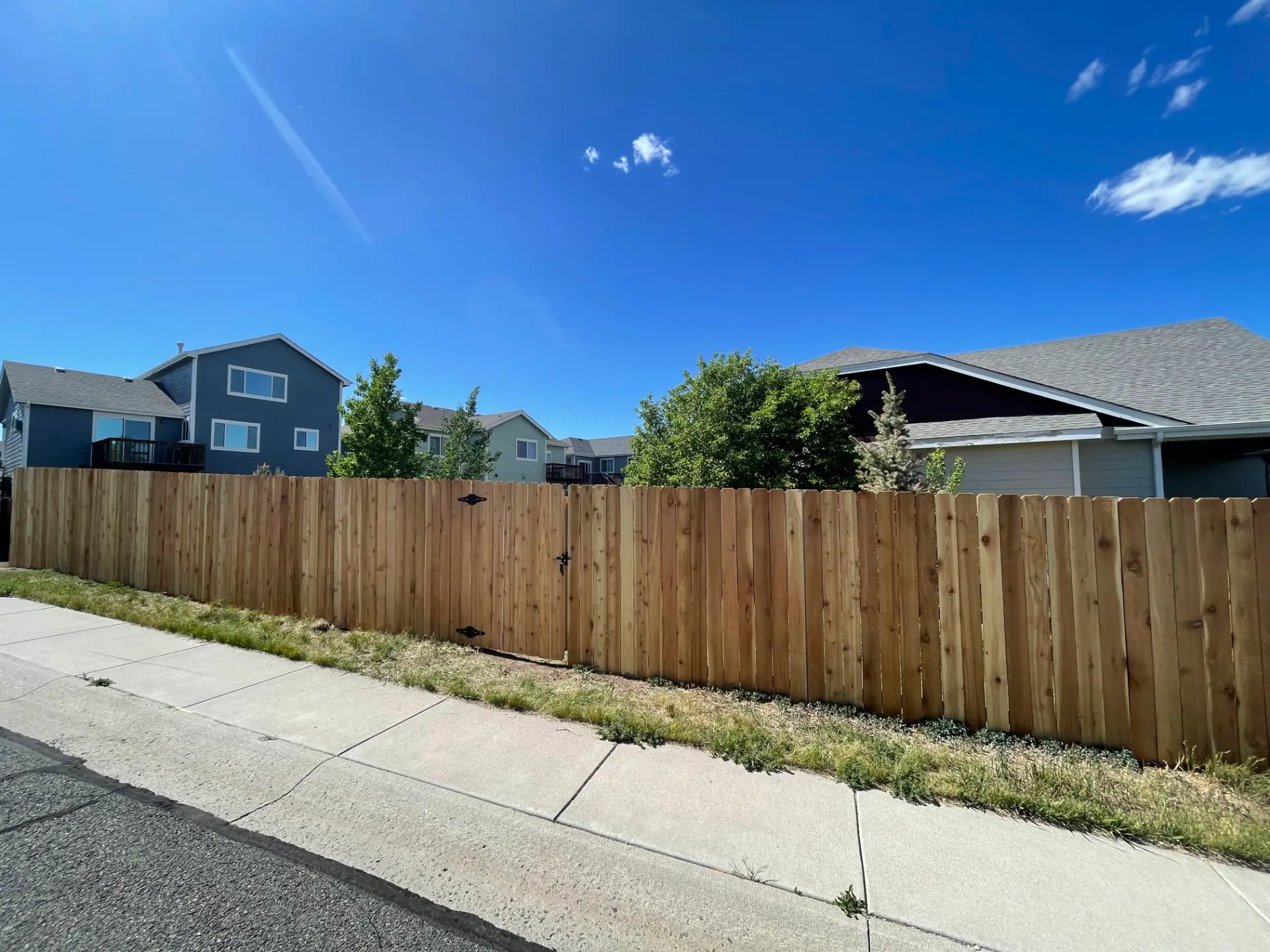 Long wood privacy fence with a matching walk gate along a residential sidewalk