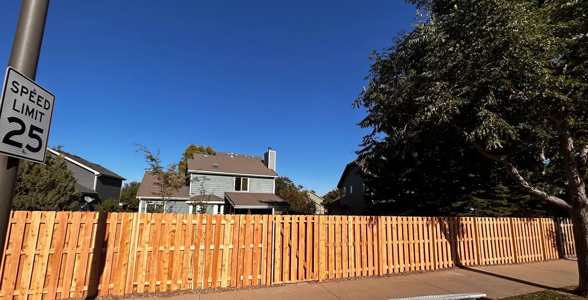 Long cedar privacy fence with a matching walk gate along a residential sidewalk