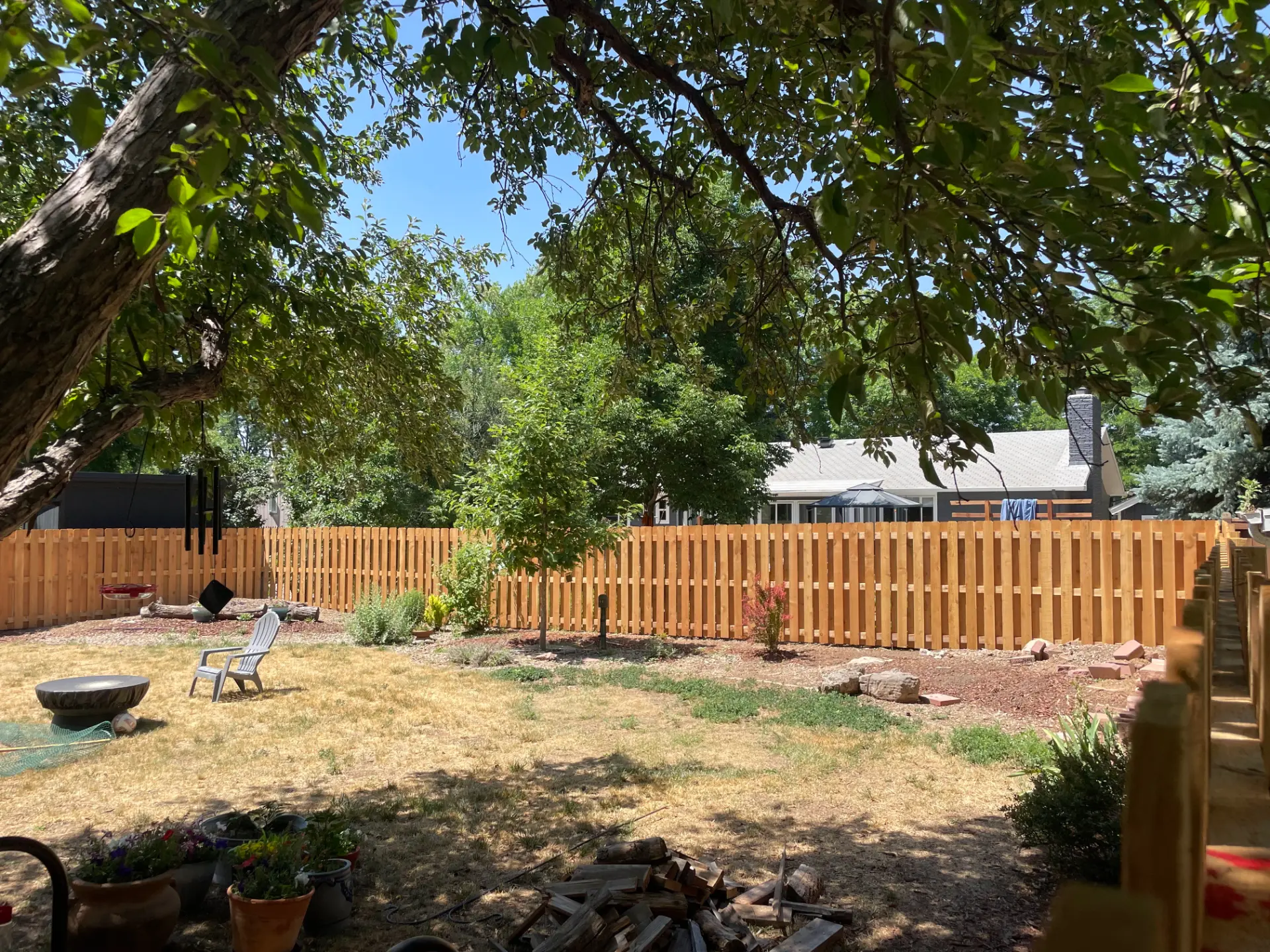 New cedar picket fence spanning a shaded residential backyard