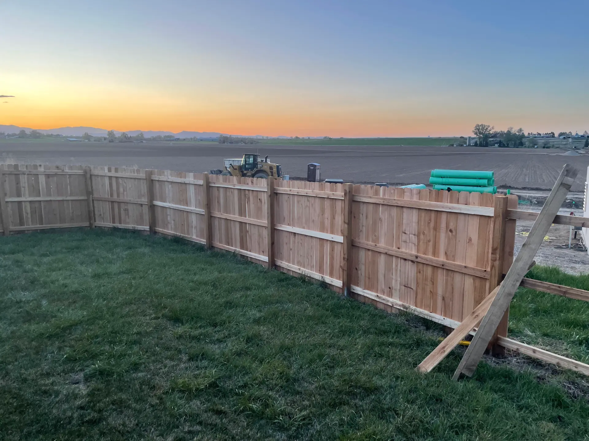 Cedar privacy fence overlooking open fields at sunset