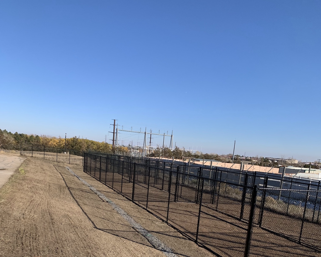 Long black chain link security fence enclosing a commercial utility site